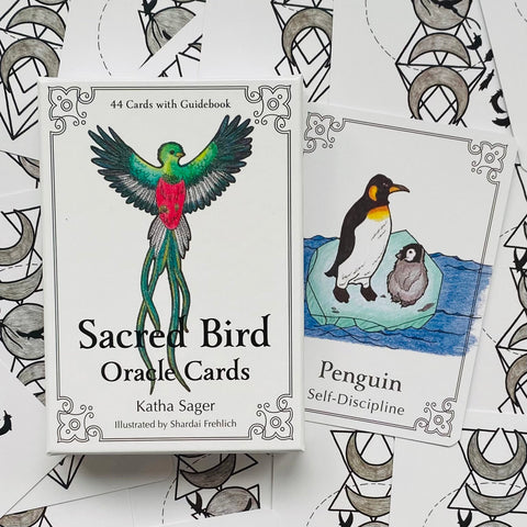 Orakulų kortos Sacred Bird dėžutė balta su spalvotu tropinio paukščio piešiniu, šalia atversta „Penguin“ korta