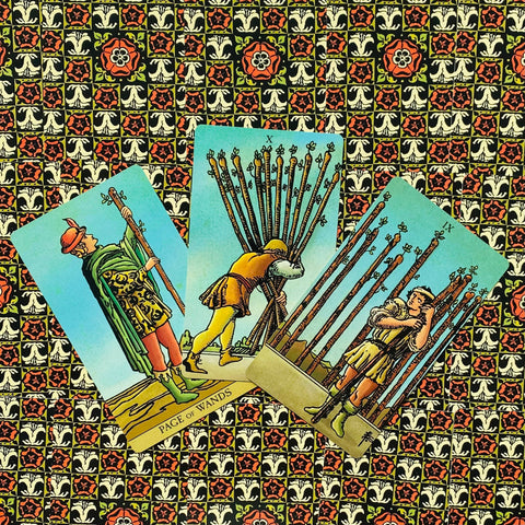 tarot kortos Rider–Waite stiliaus, trys lazdelės kortos (Page, IX ir X) atverstos ant ryškios mozaikinės grindinės, fanuotos