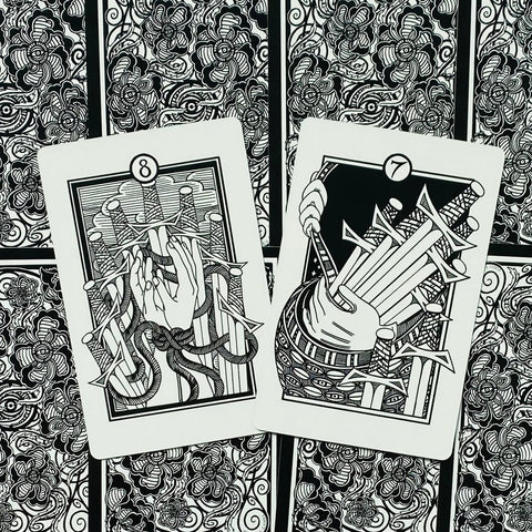 Tarot kortos juodai baltos iliustracijos, dvi atverstos kortos (8 ir 7 kardai) padėtos ant ornamentuoto nugarėlių fono