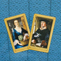 Tarot kortos su Pentaklų karaliene ir riteriu, auksu rėmintos, plokščiai išdėstytos ant mėlyno ornamentuoto fono