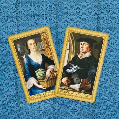 Tarot kortos su Pentaklų karaliene ir riteriu, auksu rėmintos, plokščiai išdėstytos ant mėlyno ornamentuoto fono