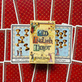 Tarot kortos Old English – geltonos dėžutės priekinis viršelis iš viršaus ant raudonų nugarėlių, matomi Five ir Six of Cups