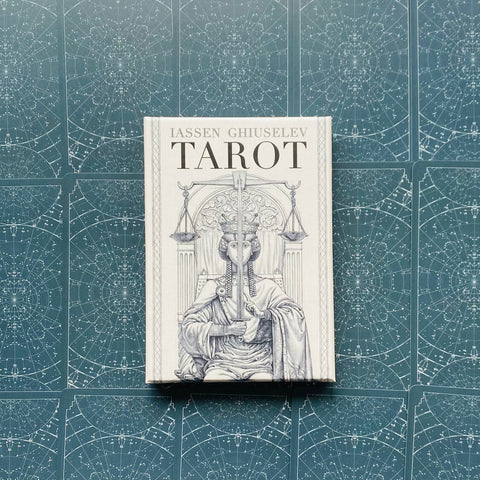 Produkto puslapio nuotrauka: Iassen Ghiuselev tarot dėžutė balta su teisingumo motyvu, padėta ant tamsiai žalių kortų nugarėlių