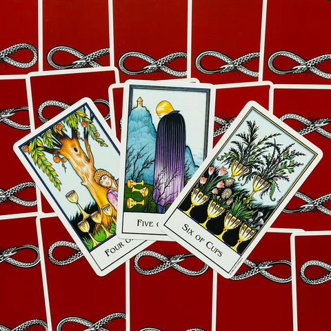 Tarot kortos Rider–Waite stiliaus – atverstos 4, 5 ir 6 taurės kortos išdėstytos ant raudonų nugarėlių su gyvatės raštu