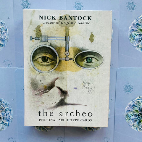 Archeo kortų rinkinys Nick Bantock, kreminėje dėžutėje su stilizuota veido ir optikos iliustracija, priekis parodytas iš viršaus