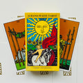 tarot kortos Albano‑Waite geltonoje dėžutėje su Saulės kortos piešiniu, dėžutės priekinė pusė ir dvi išskleistos kortos už jos