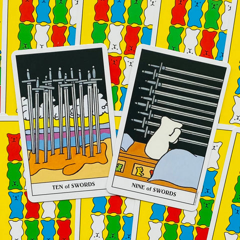 Tarot kortos Ten of Swords ir Nine of Swords ant ryškios geltonos guminių meškiukų nugarėlės, artimas kampas
