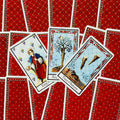 Tarot kortos su raudonomis nugarėlėmis, trys priekinės kortos parodytos arti — išsamios iliustracijos ir ornamentai