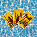 Tarot kortos Rider‑Waite stiliaus, trys atverstos Lazdų (II, III, IV) kortos ant mėlynų raštuotų nugarėlių, skirtos trijų kortų išklotai