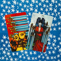 Tarot kortos, dvi įstrižai atvertos spalvotos kortos — kumščiai su virvėmis ir pririšta moteris, mėlynas žvaigždėtas fonas