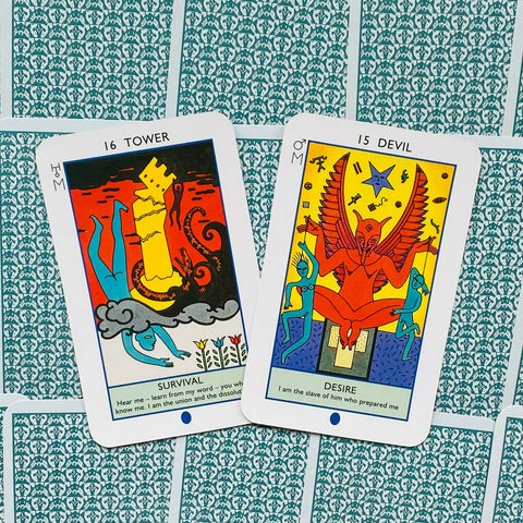 tarot kortos RWS stiliaus, dvi spalvingos kortos (Tower ir Devil) padėtos ant žalsvai raštuoto fono, artimas kampas