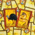 tarot kortos geltonais iliustraciniais rėmeliais, dvi atviros kortos su kasuaru (Respect) ir gyvate (Transmutation), skirtos intuityviems skaitiniams