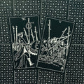Tarot kortos juodos su baltu piešiniu, dvi atverstos kortos (VI ir V) paryškintos kampu, rodo pergalę ir konfliktą