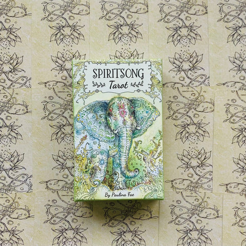 Tarot kortos Spiritsong — pastelinės žalios dėžutės priekinė dalis su ornamentuotu dramblio piešiniu, centruotos ant raštuoto fono