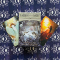 tarot kortos Tarot de la Nuit, centre matoma sidabrinė dėžutė, atverstos dvi iliustruotos kortos ir tamsiai mėlyni nugarėlių raštai