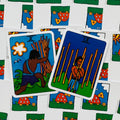 Tarot kortos Rider–Waite stiliaus: dvi priekinės kortos (Dešimt ir Devyni lazdelės) su ryškiais mėlynais fonais, nugarėlė su raudonais grybo piešiniais