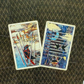 tarot kortos, dvi iliustruotos kalavijų kortos (VIII ir IX), ryškios mėlynos ir geltonos spalvos, padėtos kampu ant raštuoto tamsaus fono