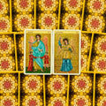 Tarot kortos Angelų oracle — dvi atverstos kortos (Anael, Sachiel) centre ant geltonos mandalos kortelių nugarų