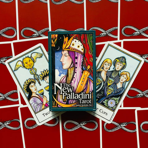 Tarot kortos New Palladini su dėžute priekyje ir trimis atverstomis kortomis ant raudonų nugarėlių fono