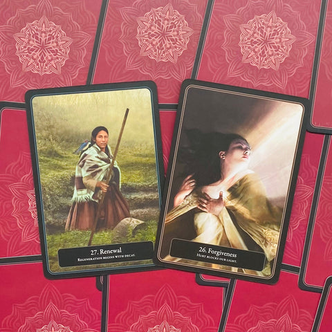 Tarot kortos su raudonais ornamentiniais nugarėliais, dvi atvertos kortos (27 Renewal, 26 Forgiveness) kampuotos, rodo iliustracijas ir stilių