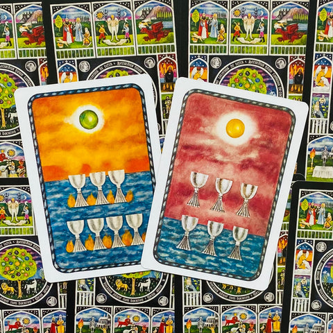 tarot kortos su dviem skirtingais dizainais — oranžine ir rožine priekine puse, matomas kupelių motyvas ant kortų fono