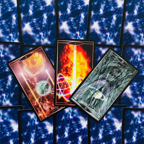 tarot kortos – trys atverstos kortos: centre ryški liepsna, kairėje kosminis motyvas, dešinėje pilkas arkos dizainas ant mėlyno nugarėlių rašto