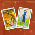 Tarot kortos Rider‑Waite stiliaus rinkinys: dvi atviros kortos (Aštuoni Pentakliai, Aštuoni Kardai) ant raudono ornamentuoto fono, šiek tiek pasvirusios