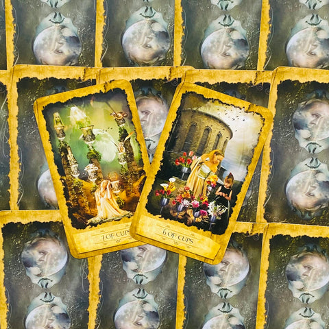 tarot kortos – atverstos 6 ir 7 taurės kortos su geltonais rėmeliais, išdėstytos ant mėnulio nugarėlių fono