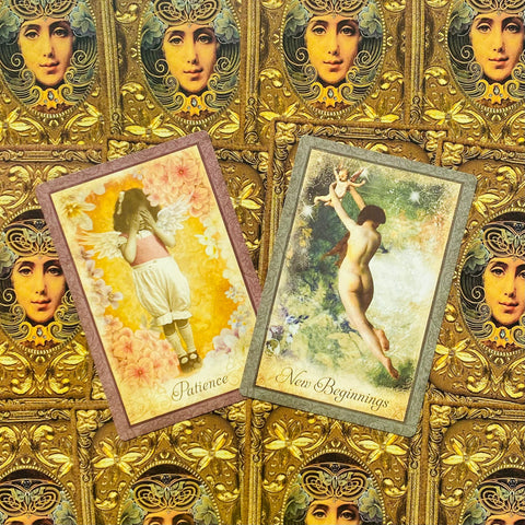 Tarot kortos su Patience ir New Beginnings iliustracijomis, pakreiptos ant auksinio ornamentuoto fono