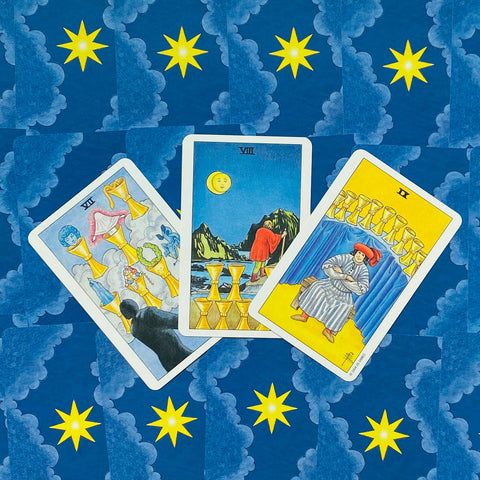 Tarot kortos Rider–Waite komplektas, trijų taurų išklotinė ant mėlyno žvaigždėto fono, kortos pasuktos skirtingais kampais