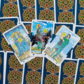 Tarot kortos Rider–Waite komplektas, trys atvertos Pentaklų kortos centre ant tamsiai mėlyno galinio dizaino