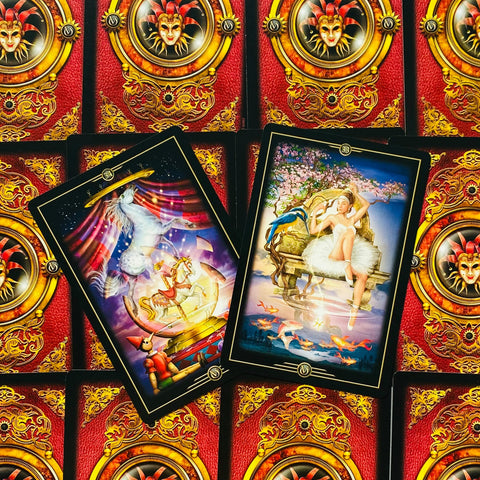 tarot kortos — dvi iliustruotos atverstos kortos ant raudonai auksinių nugarėlių fono, detalus artimas planas