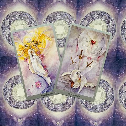 tarot kortos su akvareline estetika — dvi atviros kortos (Trijų ir Keturių kardų) ant violetinio mėnulio fono, parodytas meno variantas