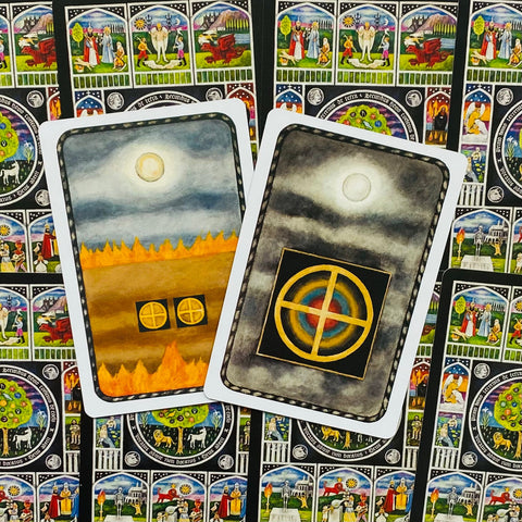 Tarot kortos dvi atverstos kortos su auksiniu kryžminiu ratu ir liepsnomis, padėtos ant spalvoto simbolinio fono, rodančios skirtingas nugarėles ir variantą kolekcijai