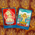 orakulo kortos: dvi atverstos kortos (White Tara ir Garuda) ant raudono-aukso ornamentuoto fono, plokščias iš viršaus