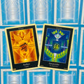 tarot kortos Amber (oranžinė) ir Amazonite (mėlyna‑žalia) pristatomos priekyje, dvi kortos persidengiančios ant mėlynos nugarėlės