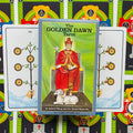 Golden Dawn Tarot dėžutė su raudonai apsirengusio karaliaus iliustracija, dvi atverstos kortos užpakalyje ir spalvingas fonas