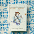 Linestrider Tarot kortų rinkinys baltame dėkle su akvareline moters iliustracija ir Siolo Thompson autorystė