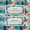 Afirmacijų kortos su jūros iliustracijomis, dvi kortos „Listen“ ir „Meditate“ ant undinių raštuoto fono