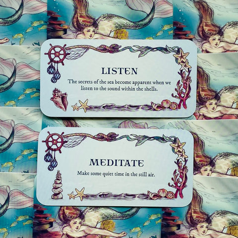 Afirmacijų kortos su jūros iliustracijomis, dvi kortos „Listen“ ir „Meditate“ ant undinių raštuoto fono
