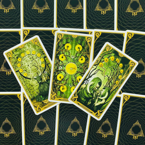 Tarot kortos su žaliais pentaklių piešiniais, trys atverstos kortos ant juodai auksinių nugarėlių rodant skirtingus dizainus ir detales