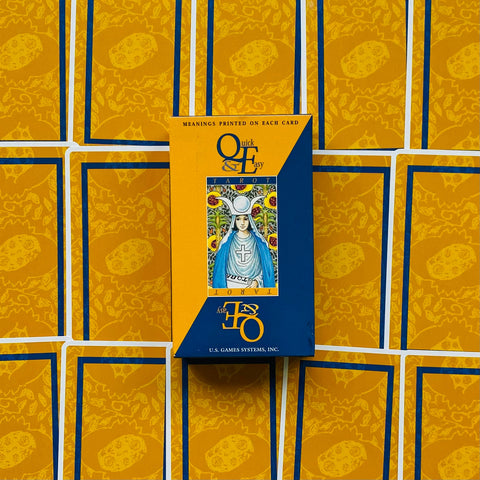 Tarot kortos Quick & Easy, geltonai‑mėlyna dėžutė centre ant išskleistų kortų nugarėlių, matomas prekės dizainas
