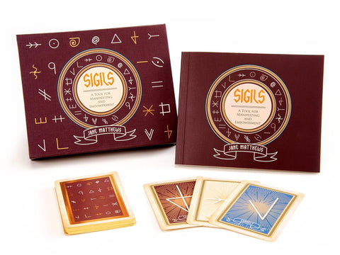 Kortų rinkinys "Sigils" su bordo dėže ir vadovu ant balto fono, išskleistos kortos su mėlyna, ruda ir smėlio nugarėlėmis