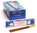 Nag Champa smilkalai Satya, mėlyna 15 g pakuotė su keliomis rudos spalvos lazdelėmis priekyje ir didesne dėžute fone