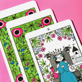 Tarot kortos fanuotos trys kortos, iliustruotas karalius kortoje, ryškios žalios gėlėtos nugarėlės ir rožinis fonas