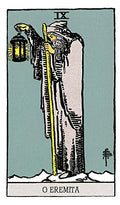Tarot korta Eremitas (Rider–Waite) — vertikalus artimas kadras, pilkas apsiaustas ir geltonas žibintas meditacijai