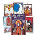 Aquarian Tarot kortos su pridedamu gidų leidiniu, purpurinės viršelio spalvos dėžutė ir kelios išskleistos kortos priešakyje
