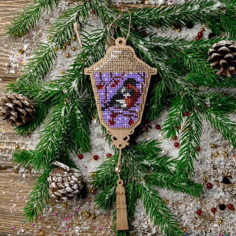 Medinė lempelės formos kalėdinė dekoracija su violetine karoliukų aplikacija ir raudonpilviu paukšteliu, priekinis vaizdas ant eglės šakų