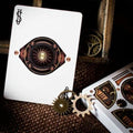 Kortų kaladė steampunk, baltos kortos su varinės spalvos mechanine tūrine ace detale ir metalinėmis krumpliaračių dekoracijomis, artimas kampas