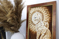 paveikslas rėmuotas medinis su stilizuota saulės ir katės raižyta ornamentika, rudos tonų paletė, šalia vaza su pampas žolėmis